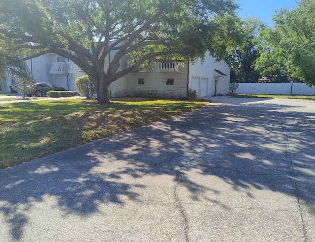 view of home's exterior with a lawn, driveway, and fence