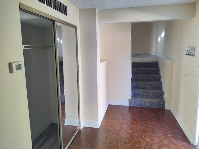 stairway with baseboards, visible vents, tile patterned flooring, and a textured ceiling