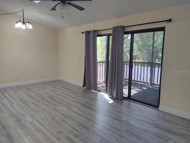 unfurnished room featuring ceiling fan with notable chandelier, baseboards, a textured ceiling, and wood finished floors