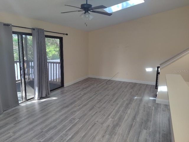 empty room with baseboards, wood finished floors, and a ceiling fan