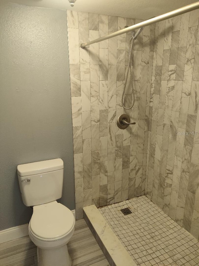 full bathroom with baseboards, toilet, and a stall shower