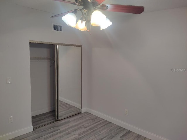 unfurnished bedroom featuring a closet, a ceiling fan, light wood-type flooring, baseboards, and visible vents