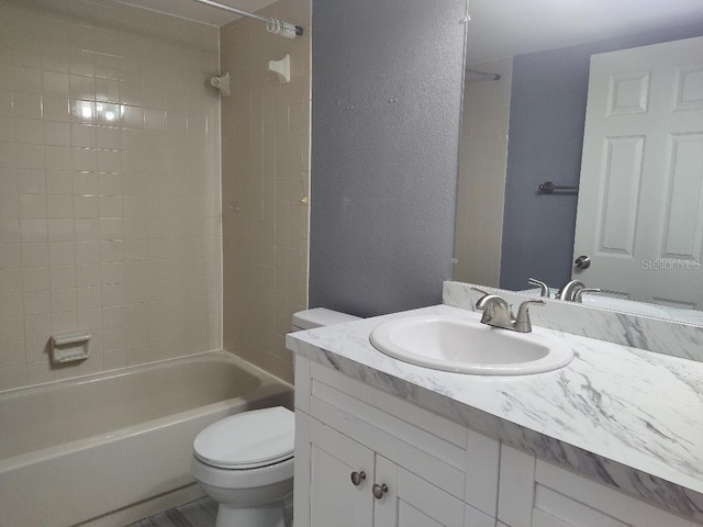 bathroom featuring shower / bathing tub combination, a textured wall, toilet, and vanity