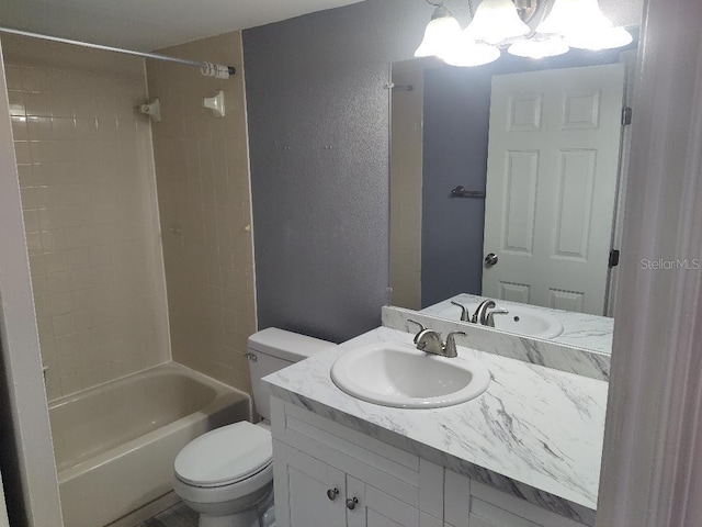 bathroom featuring vanity, an inviting chandelier, toilet, a textured wall, and bathtub / shower combination