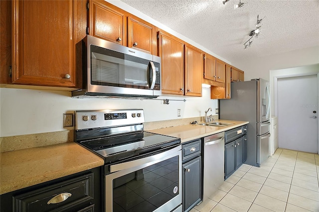 kitchen featuring a sink, a textured ceiling, appliances with stainless steel finishes, and light countertops