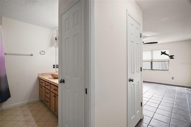 bathroom with a textured ceiling, baseboards, tile patterned flooring, and vanity