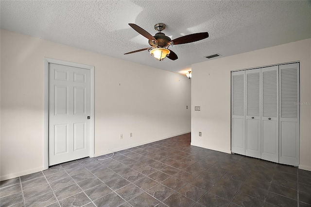 unfurnished bedroom featuring a ceiling fan, a closet, a textured ceiling, and visible vents