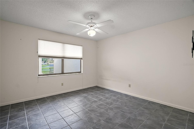 empty room featuring baseboards, ceiling fan, dark tile patterned floors, and a textured ceiling