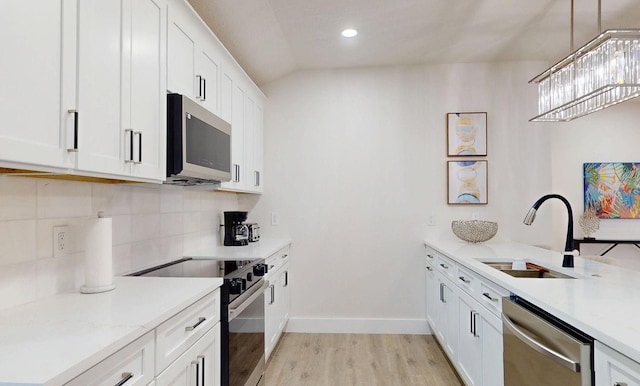 4530 5th Ave S, Saint Petersburg, FL 33711 - kitchen with stainless steel appliances, a sink, light wood-type flooring, tasteful backsplash, and white cabinetry