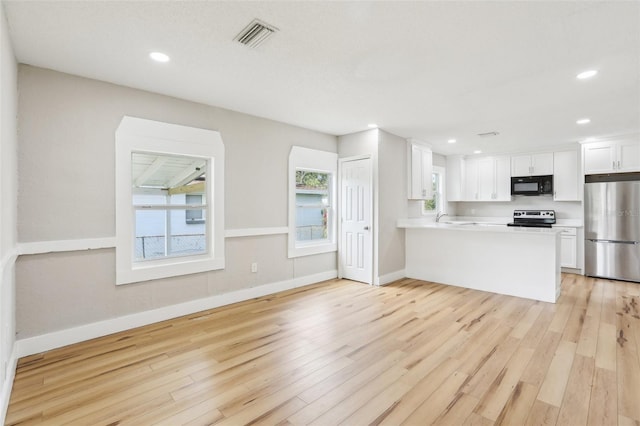 2920 E 20th Ave, Tampa, FL 33605 - kitchen with light countertops, light wood-type flooring, stainless steel appliances, visible vents, and white cabinets