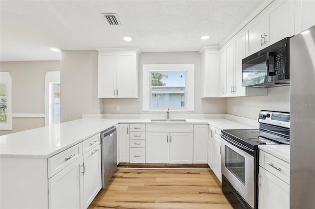 2920 E 20th Ave, Tampa, FL 33605 - kitchen with a sink, light wood finished floors, visible vents, a peninsula, and appliances with stainless steel finishes