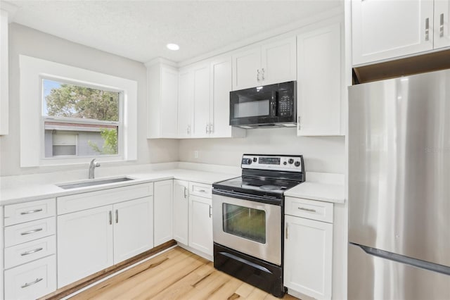 2920 E 20th Ave, Tampa, FL 33605 - kitchen with white cabinetry, light countertops, a sink, light wood-style floors, and appliances with stainless steel finishes