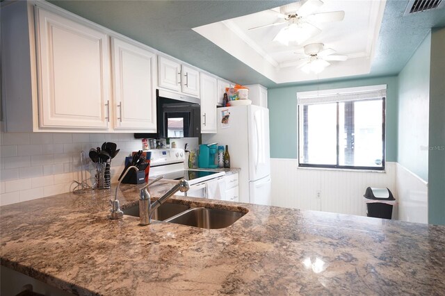 7360 Ulmerton Rd Unit 29B, Largo, FL 33771 - kitchen featuring white appliances, a raised ceiling, dark stone counters, ceiling fan, and a wainscoted wall