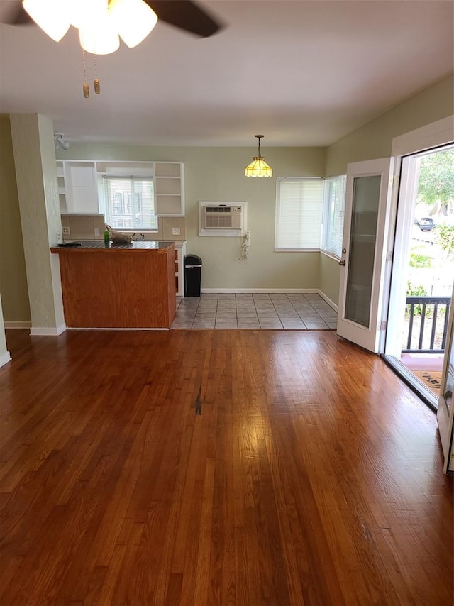548 3rd St N, Saint Petersburg, FL 33701 - unfurnished living room featuring baseboards, hardwood / wood-style flooring, an AC wall unit, and a ceiling fan