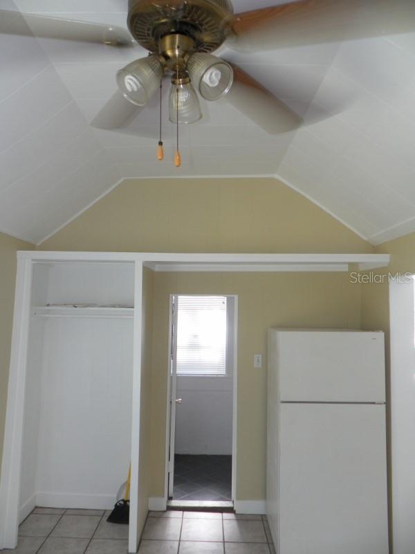 548 3rd St N, Saint Petersburg, FL 33701 - interior space featuring light tile patterned floors, vaulted ceiling, freestanding refrigerator, and ceiling fan