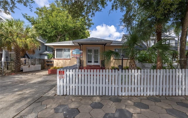 548 3rd St N, Saint Petersburg, FL 33701 - view of front of home with concrete driveway, french doors, stucco siding, and a fenced front yard