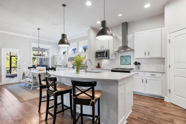 14241 Natures Reserve Dr, Lithia, FL 33547 - kitchen with wall chimney range hood, appliances with stainless steel finishes, a sink, an island with sink, and tasteful backsplash