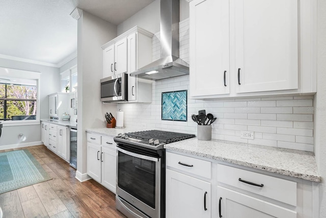 14241 Natures Reserve Dr, Lithia, FL 33547 - kitchen with wall chimney exhaust hood, appliances with stainless steel finishes, beverage cooler, wood finished floors, and white cabinets