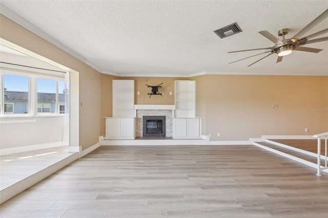 3252 Scorecard Dr, New Port Richey, FL 34655 - unfurnished living room with visible vents, light wood-type flooring, a glass covered fireplace, a textured ceiling, and ceiling fan