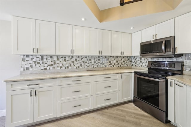 3252 Scorecard Dr, New Port Richey, FL 34655 - kitchen with decorative backsplash, light wood-style floors, stainless steel appliances, white cabinets, and recessed lighting