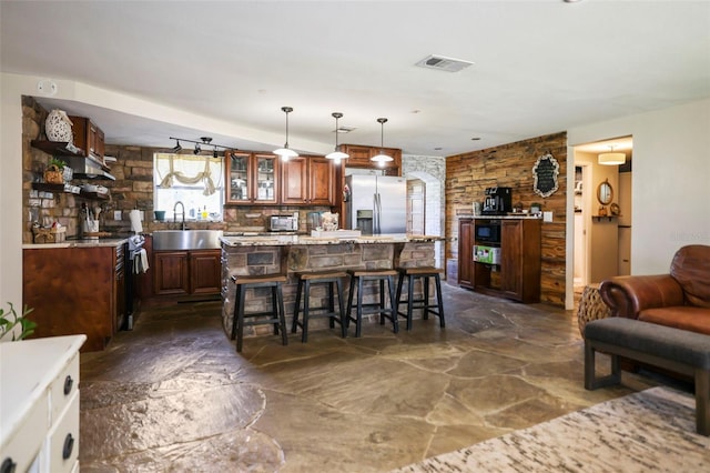 9825 Casey Dr, New Port Richey, FL 34654 - kitchen with a breakfast bar, stone flooring, a center island, glass insert cabinets, and stainless steel refrigerator with ice dispenser