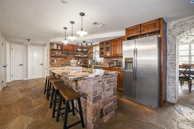 9825 Casey Dr, New Port Richey, FL 34654 - kitchen featuring open shelves, stainless steel fridge with ice dispenser, tasteful backsplash, brown cabinetry, and visible vents