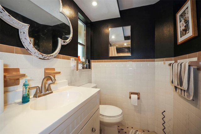9825 Casey Dr, New Port Richey, FL 34654 - full bathroom featuring vanity, tile walls, recessed lighting, toilet, and a wainscoted wall