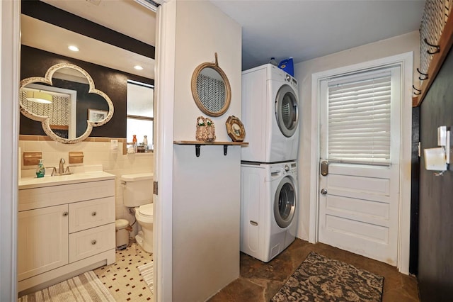 9825 Casey Dr, New Port Richey, FL 34654 - laundry room featuring a sink, tile walls, laundry area, and stacked washer / drying machine