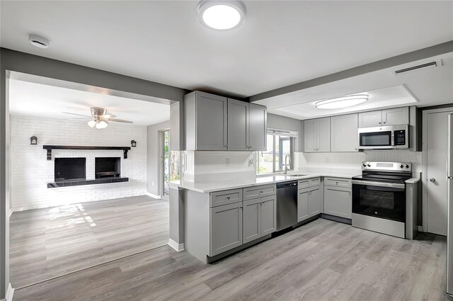 kitchen featuring a sink, a ceiling fan, gray cabinetry, light wood-type flooring, and stainless steel appliances