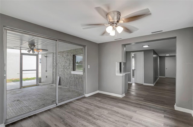 unfurnished room with wood finished floors, visible vents, plenty of natural light, and ceiling fan