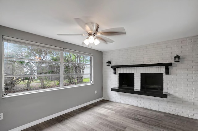 unfurnished living room featuring a ceiling fan, baseboards, a fireplace, and wood finished floors