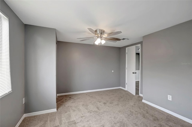 empty room featuring carpet flooring, visible vents, baseboards, and ceiling fan