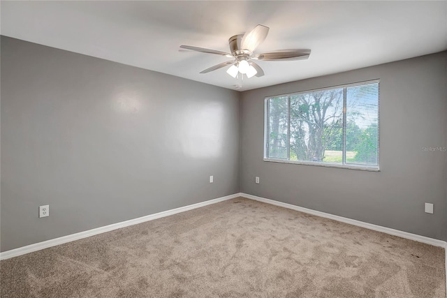 carpeted empty room with a ceiling fan and baseboards