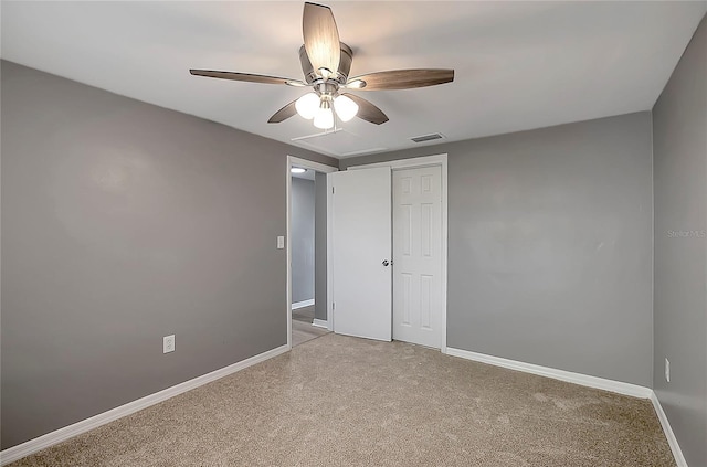 unfurnished bedroom with light colored carpet, a closet, a ceiling fan, baseboards, and visible vents