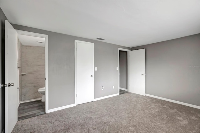 unfurnished bedroom featuring baseboards, carpet flooring, visible vents, and ensuite bath