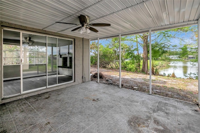 unfurnished sunroom featuring a healthy amount of sunlight, a water view, and a ceiling fan