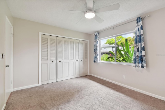 unfurnished bedroom with a closet, a textured ceiling, carpet, baseboards, and a ceiling fan