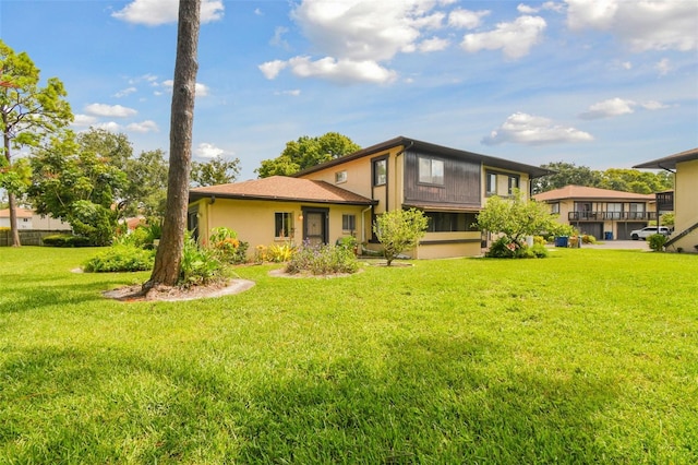 rear view of property with stucco siding and a yard