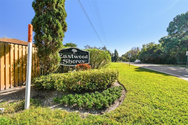 community / neighborhood sign featuring fence and a yard