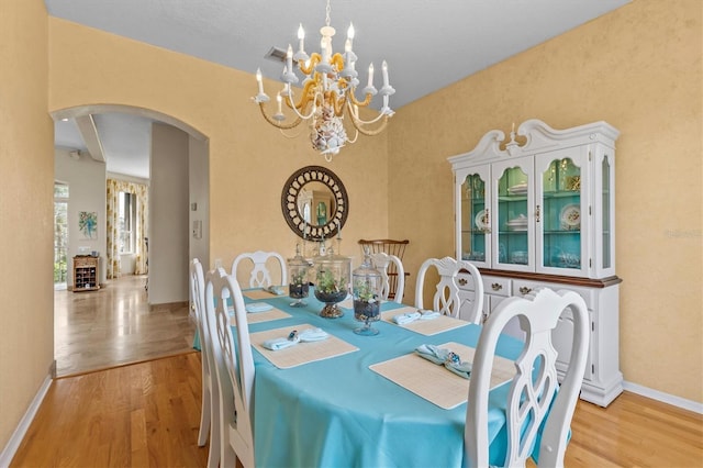 2050 N Pointe Alexis Dr, Tarpon Springs, FL 34689 - dining area featuring baseboards, wood finished floors, arched walkways, and an inviting chandelier
