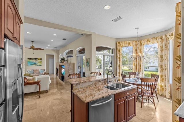 2050 N Pointe Alexis Dr, Tarpon Springs, FL 34689 - kitchen with light stone counters, a sink, appliances with stainless steel finishes, a center island with sink, and ceiling fan with notable chandelier