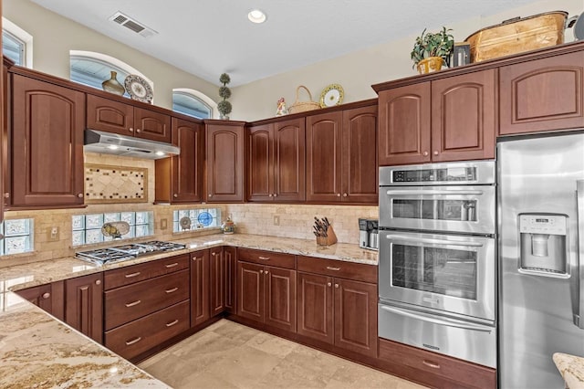 2050 N Pointe Alexis Dr, Tarpon Springs, FL 34689 - kitchen featuring a warming drawer, under cabinet range hood, visible vents, light stone countertops, and appliances with stainless steel finishes