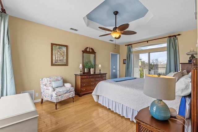 2050 N Pointe Alexis Dr, Tarpon Springs, FL 34689 - bedroom with access to exterior, visible vents, light wood-type flooring, and a raised ceiling