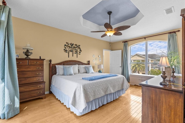 2050 N Pointe Alexis Dr, Tarpon Springs, FL 34689 - bedroom with a tray ceiling, a textured ceiling, light wood-style flooring, visible vents, and ceiling fan