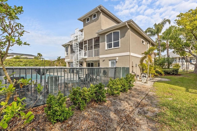2050 N Pointe Alexis Dr, Tarpon Springs, FL 34689 - rear view of house featuring fence, stairs, a fenced in pool, a lawn, and stucco siding