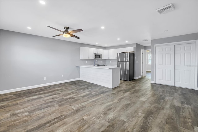 9105 W Hillsborough Ave Unit I102, Tampa, FL 33615 - kitchen featuring dark wood-style flooring, visible vents, a peninsula, a ceiling fan, and appliances with stainless steel finishes