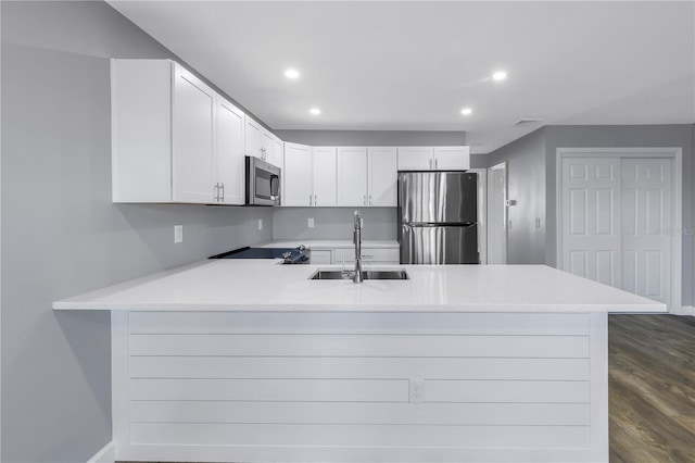 9105 W Hillsborough Ave Unit I102, Tampa, FL 33615 - kitchen featuring light countertops, a peninsula, appliances with stainless steel finishes, white cabinetry, and a sink