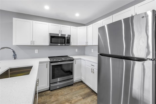 9105 W Hillsborough Ave Unit I102, Tampa, FL 33615 - kitchen with white cabinets, wood finished floors, stainless steel appliances, recessed lighting, and a sink