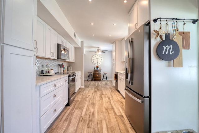 8326 Archwood Cir, Tampa, FL 33615 - kitchen with baseboards, appliances with stainless steel finishes, white cabinetry, light wood-style floors, and backsplash