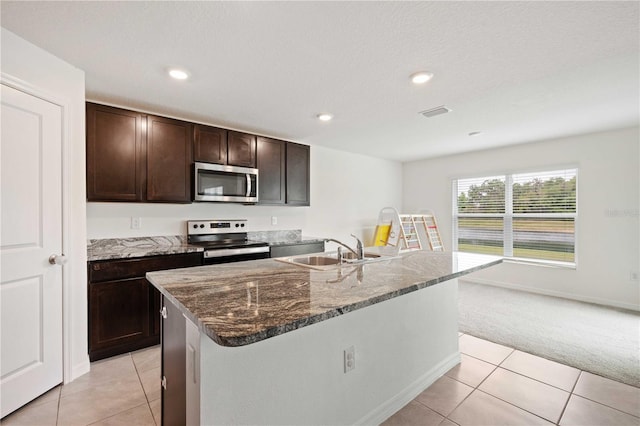 kitchen with light tile patterned flooring, a sink, light carpet, stainless steel appliances, and dark stone counters